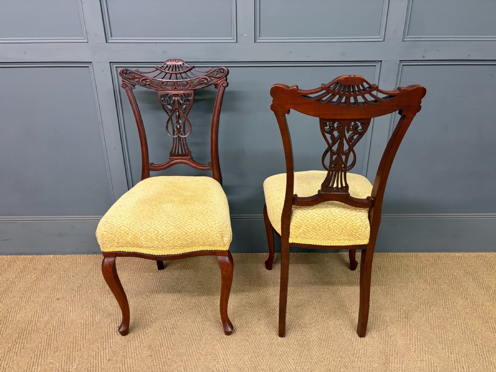 A seven-piece Victorian mahogany salon suite comprising a carved settee, two armchairs, and four side chairs, all upholstered in yellow patterned fabric. View IV