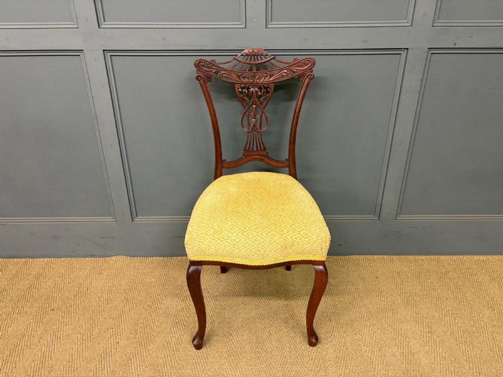 A seven-piece Victorian mahogany salon suite comprising a carved settee, two armchairs, and four side chairs, all upholstered in yellow patterned fabric. View V