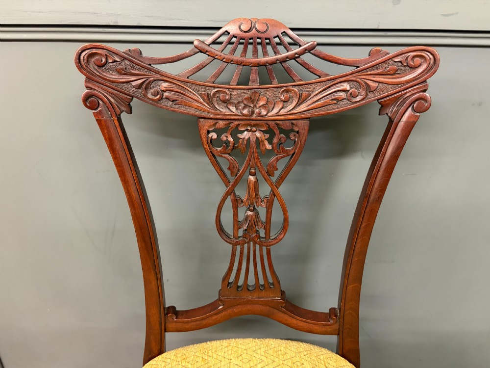A seven-piece Victorian mahogany salon suite comprising a carved settee, two armchairs, and four side chairs, all upholstered in yellow patterned fabric. View VI