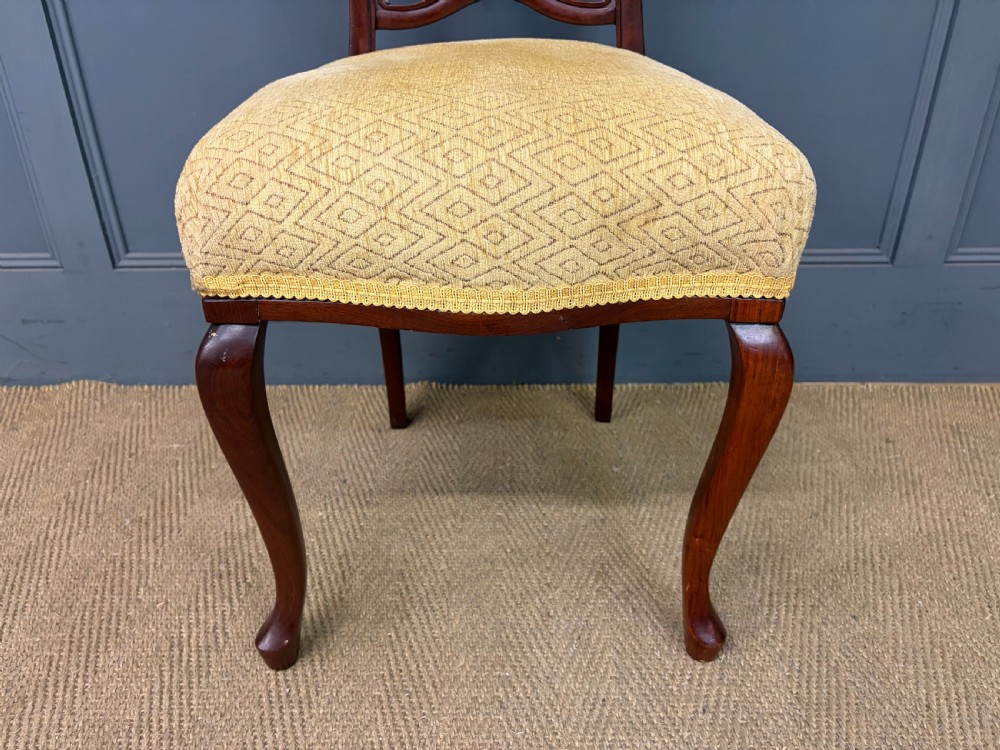 A seven-piece Victorian mahogany salon suite comprising a carved settee, two armchairs, and four side chairs, all upholstered in yellow patterned fabric. View VIII
