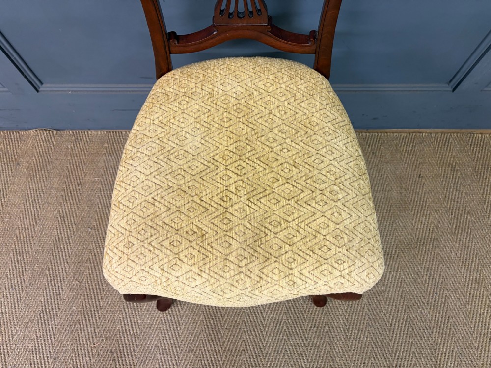 A seven-piece Victorian mahogany salon suite comprising a carved settee, two armchairs, and four side chairs, all upholstered in yellow patterned fabric. View IX