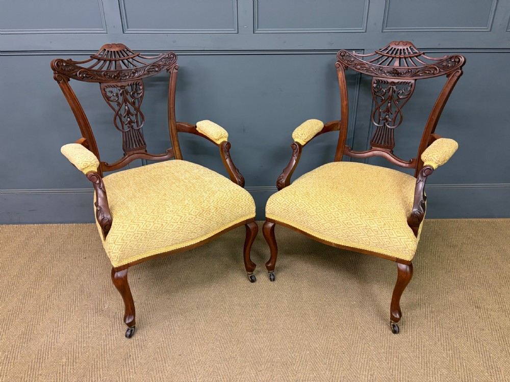 A seven-piece Victorian mahogany salon suite comprising a carved settee, two armchairs, and four side chairs, all upholstered in yellow patterned fabric. View XI