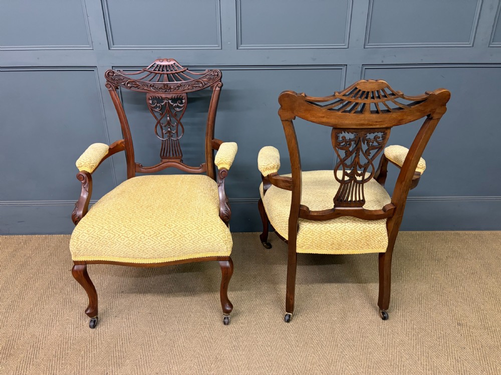 A seven-piece Victorian mahogany salon suite comprising a carved settee, two armchairs, and four side chairs, all upholstered in yellow patterned fabric. View XIV
