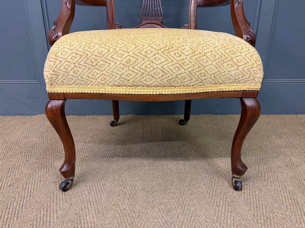 A seven-piece Victorian mahogany salon suite comprising a carved settee, two armchairs, and four side chairs, all upholstered in yellow patterned fabric. View XVI