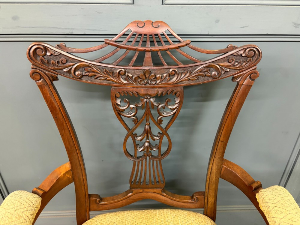 A seven-piece Victorian mahogany salon suite comprising a carved settee, two armchairs, and four side chairs, all upholstered in yellow patterned fabric. View XVIII