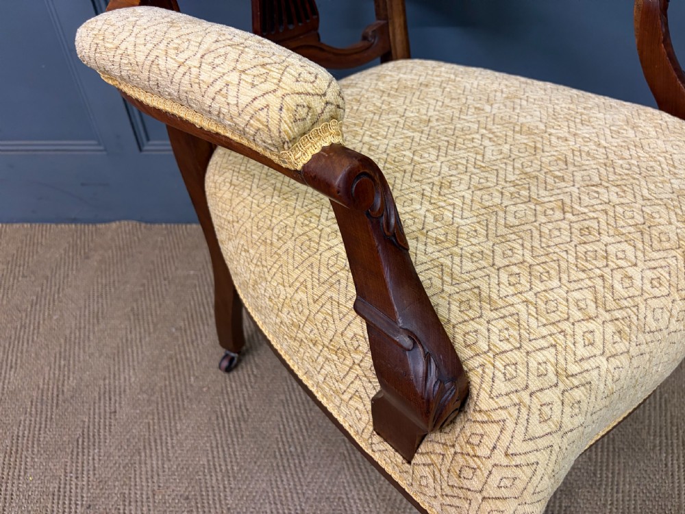 A seven-piece Victorian mahogany salon suite comprising a carved settee, two armchairs, and four side chairs, all upholstered in yellow patterned fabric. View XX