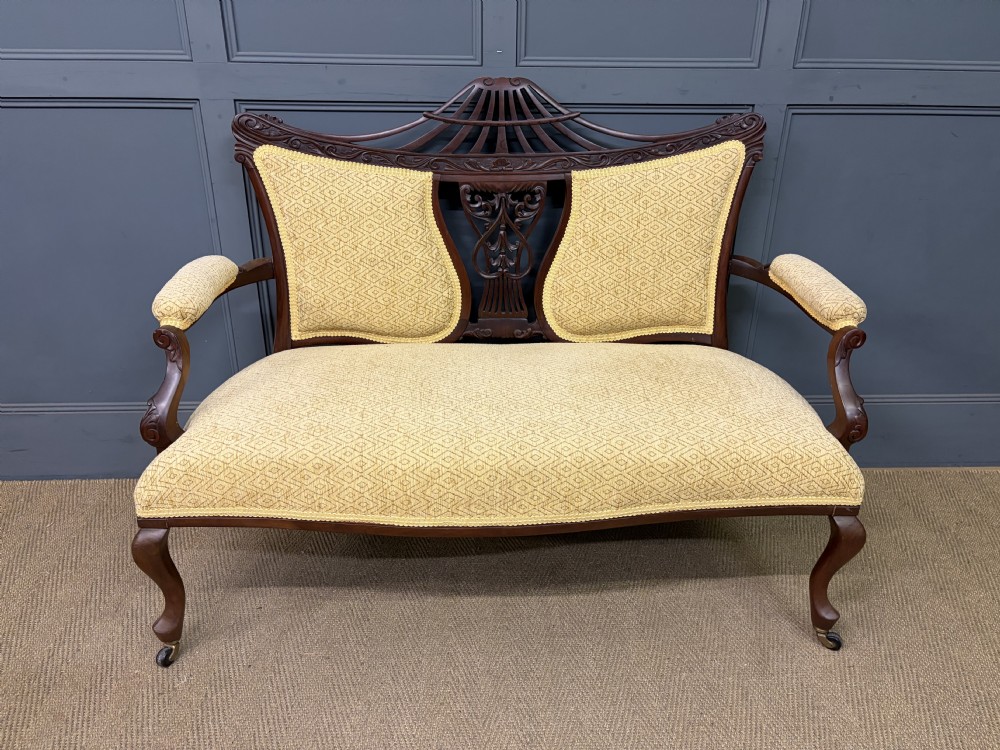 A seven-piece Victorian mahogany salon suite comprising a carved settee, two armchairs, and four side chairs, all upholstered in yellow patterned fabric. View XXI