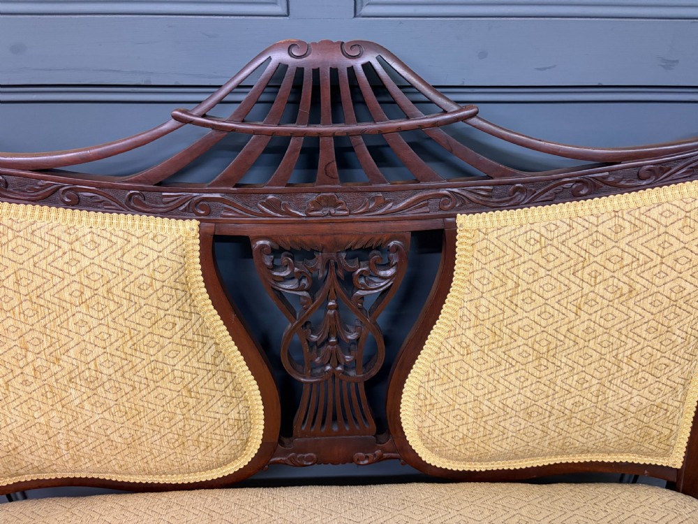 A seven-piece Victorian mahogany salon suite comprising a carved settee, two armchairs, and four side chairs, all upholstered in yellow patterned fabric. View XXIII