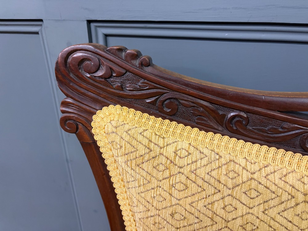 A seven-piece Victorian mahogany salon suite comprising a carved settee, two armchairs, and four side chairs, all upholstered in yellow patterned fabric. View XXIV