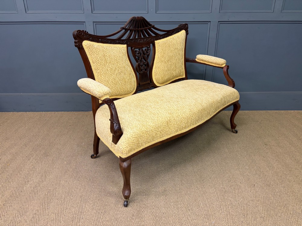 A seven-piece Victorian mahogany salon suite comprising a carved settee, two armchairs, and four side chairs, all upholstered in yellow patterned fabric. View XXVI