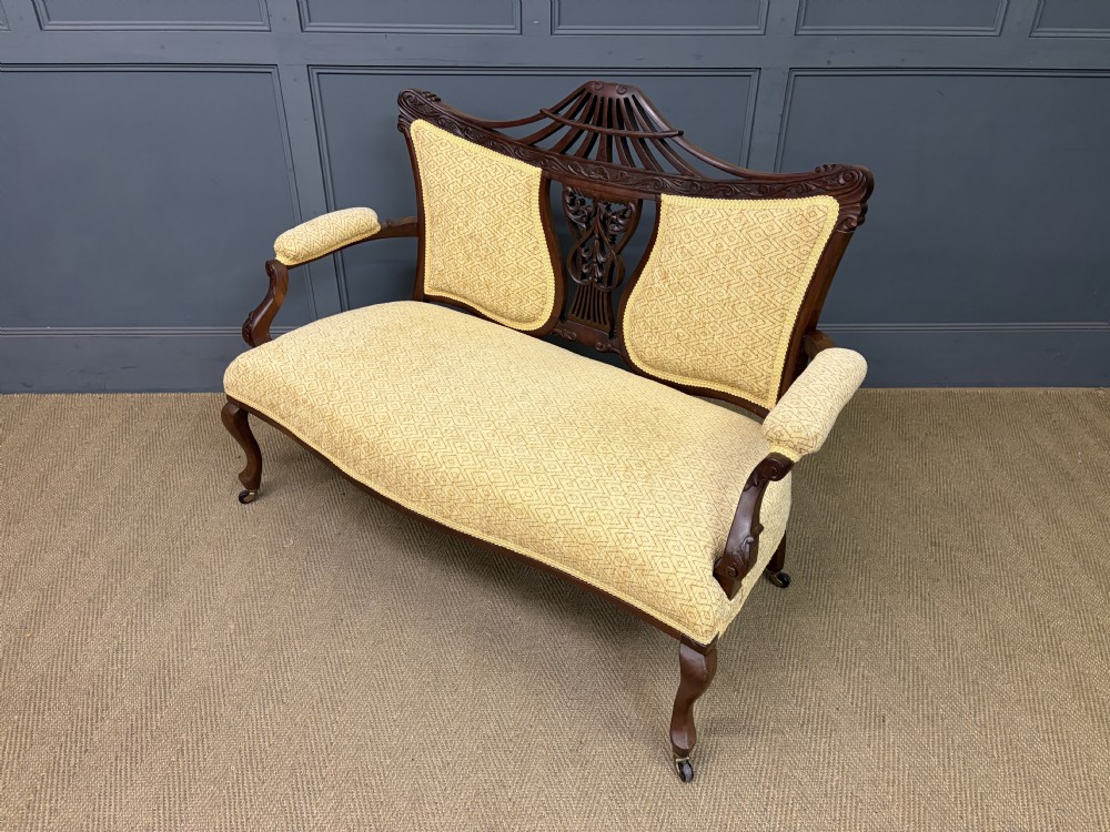 A seven-piece Victorian mahogany salon suite comprising a carved settee, two armchairs, and four side chairs, all upholstered in yellow patterned fabric. View XXVII
