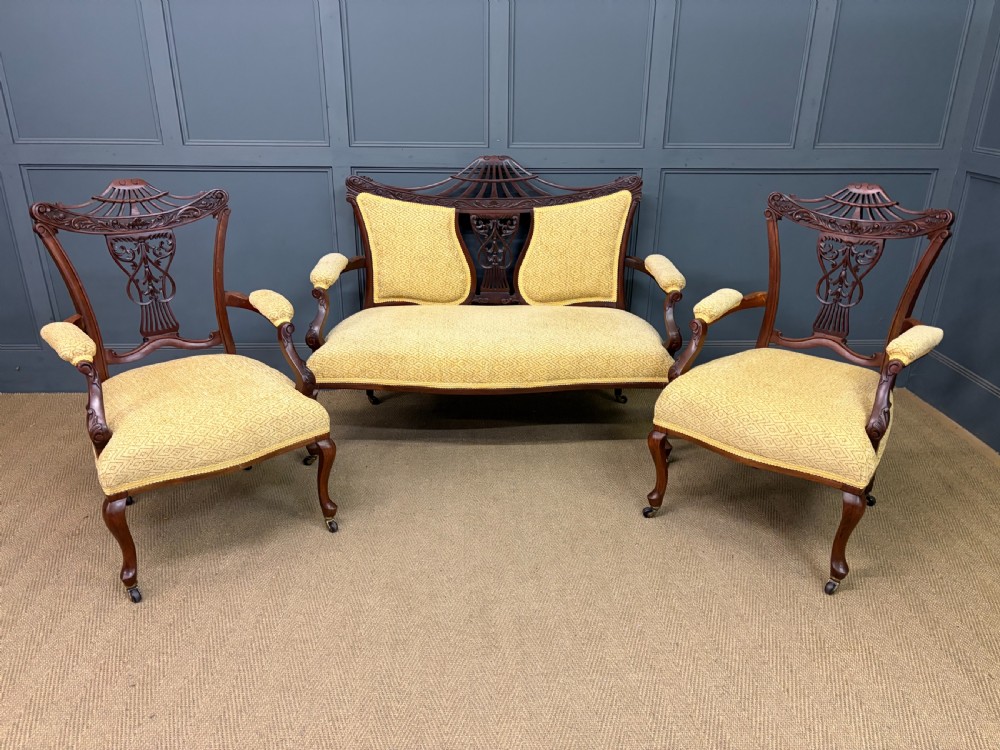 A seven-piece Victorian mahogany salon suite comprising a carved settee, two armchairs, and four side chairs, all upholstered in yellow patterned fabric. View XXIX