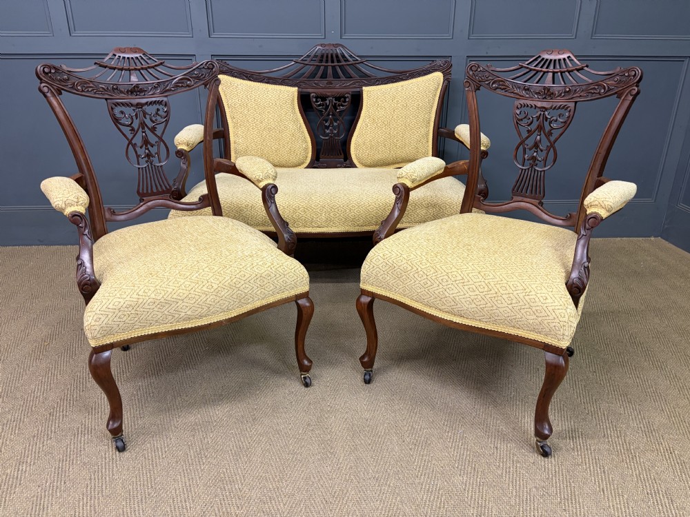 A seven-piece Victorian mahogany salon suite comprising a carved settee, two armchairs, and four side chairs, all upholstered in yellow patterned fabric. View XXX