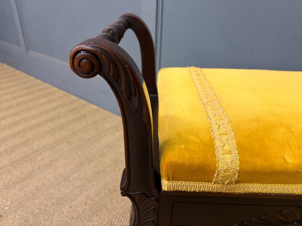 An antique dark mahogany piano stool featuring carved cabriole legs, scroll side handles, a carved shell apron motif, and a padded yellow velvet seat. View IX