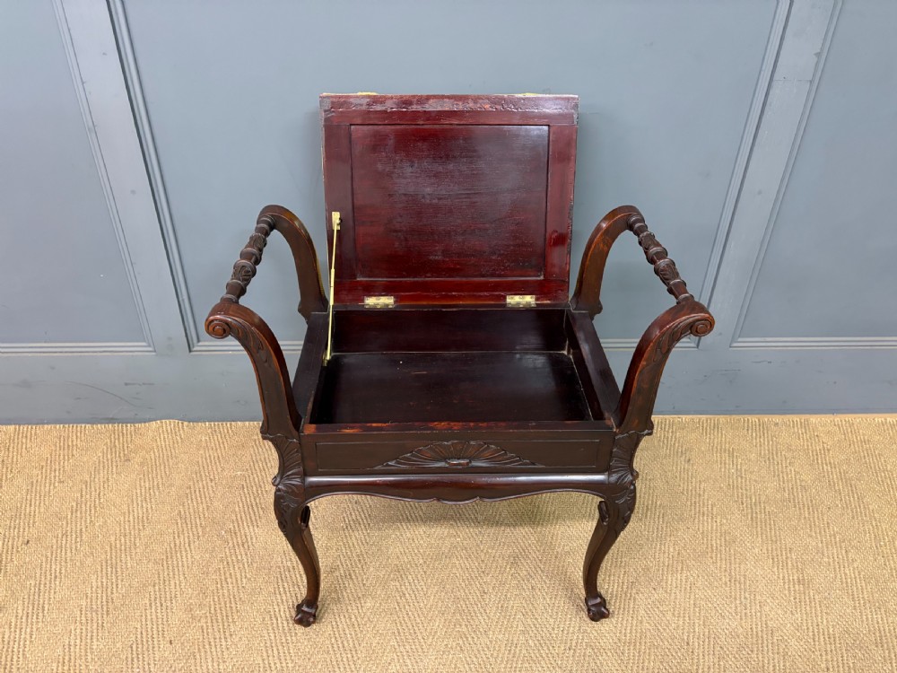 An antique dark mahogany piano stool featuring carved cabriole legs, scroll side handles, a carved shell apron motif, and a padded yellow velvet seat. View XI