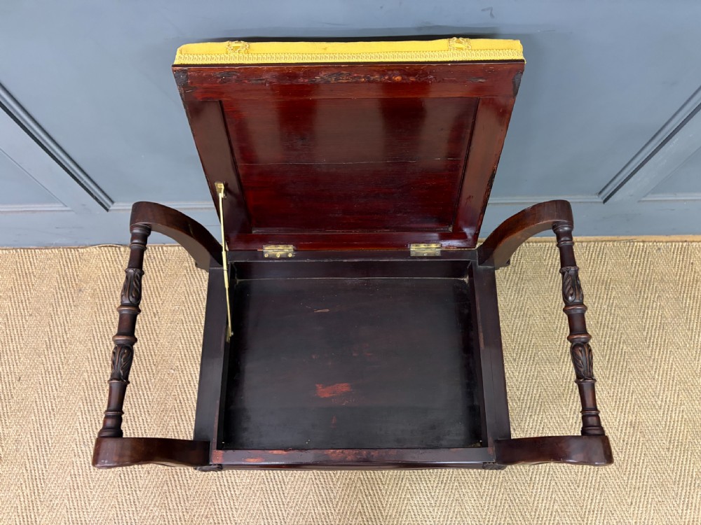 An antique dark mahogany piano stool featuring carved cabriole legs, scroll side handles, a carved shell apron motif, and a padded yellow velvet seat. View XIV