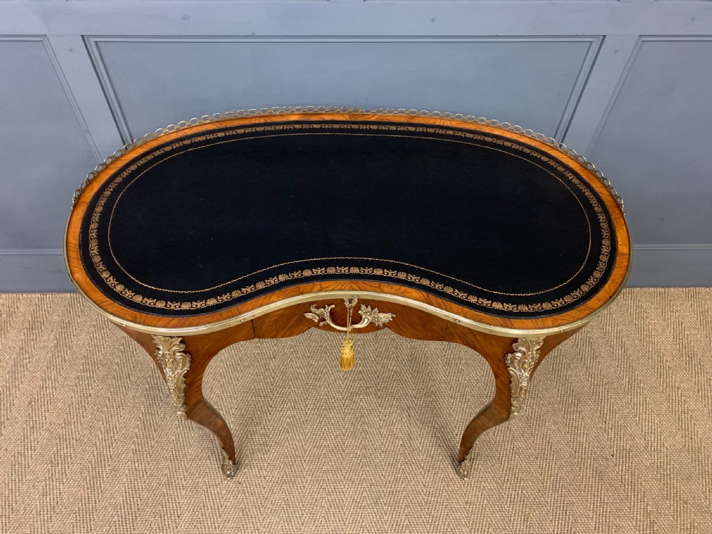 A Victorian kidney-shaped rosewood writing table featuring a dark leather top with gilt tooling, a pierced brass gallery, and cabriole legs with decorative ormolu mounts. View II
