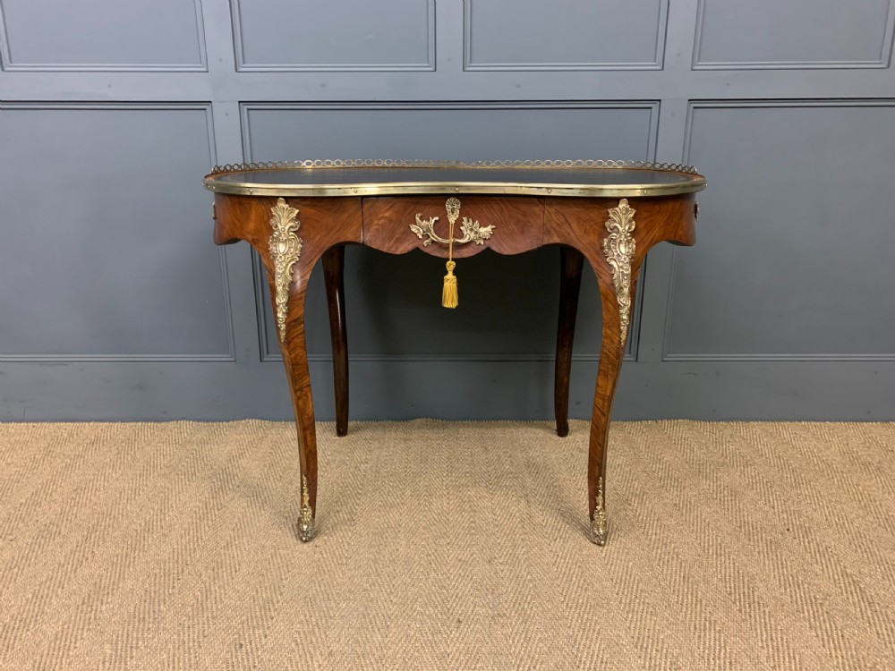 A Victorian kidney-shaped rosewood writing table featuring a dark leather top with gilt tooling, a pierced brass gallery, and cabriole legs with decorative ormolu mounts. View III