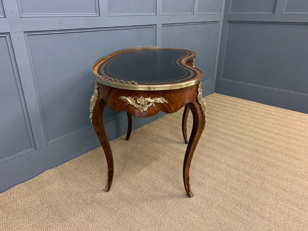 A Victorian kidney-shaped rosewood writing table featuring a dark leather top with gilt tooling, a pierced brass gallery, and cabriole legs with decorative ormolu mounts. View XI