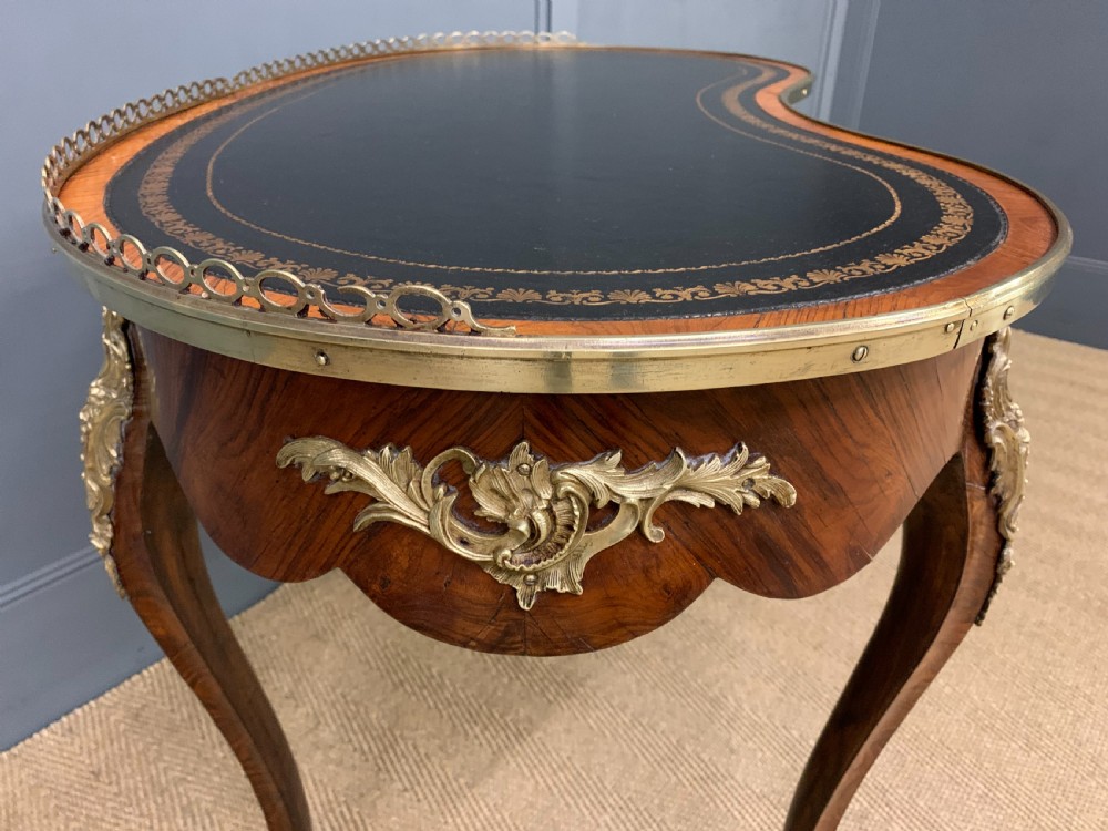 A Victorian kidney-shaped rosewood writing table featuring a dark leather top with gilt tooling, a pierced brass gallery, and cabriole legs with decorative ormolu mounts. View XII