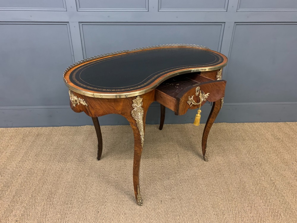 A Victorian kidney-shaped rosewood writing table featuring a dark leather top with gilt tooling, a pierced brass gallery, and cabriole legs with decorative ormolu mounts. View XIII