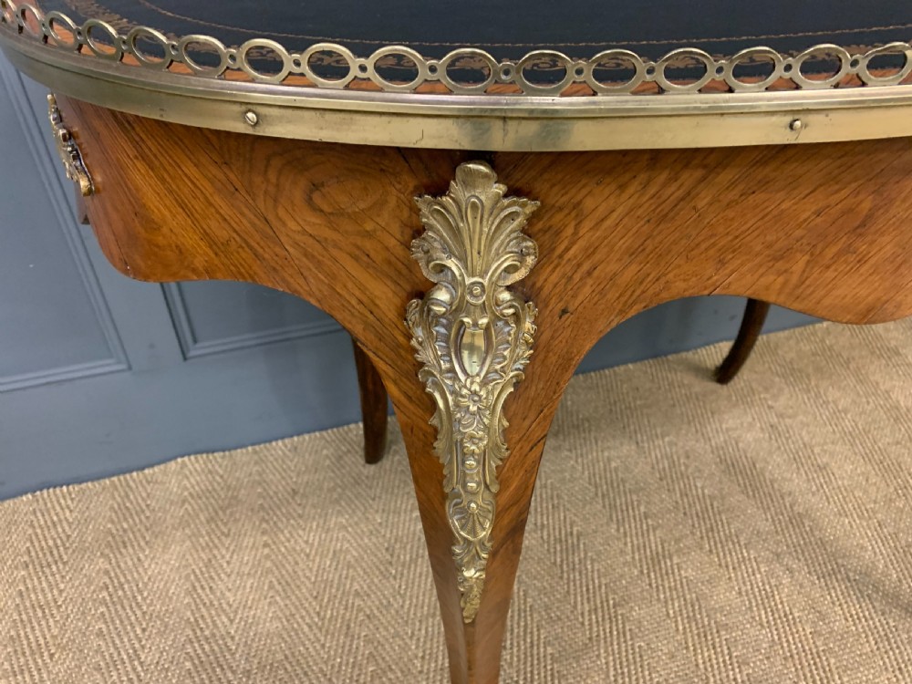 A Victorian kidney-shaped rosewood writing table featuring a dark leather top with gilt tooling, a pierced brass gallery, and cabriole legs with decorative ormolu mounts. View XVII