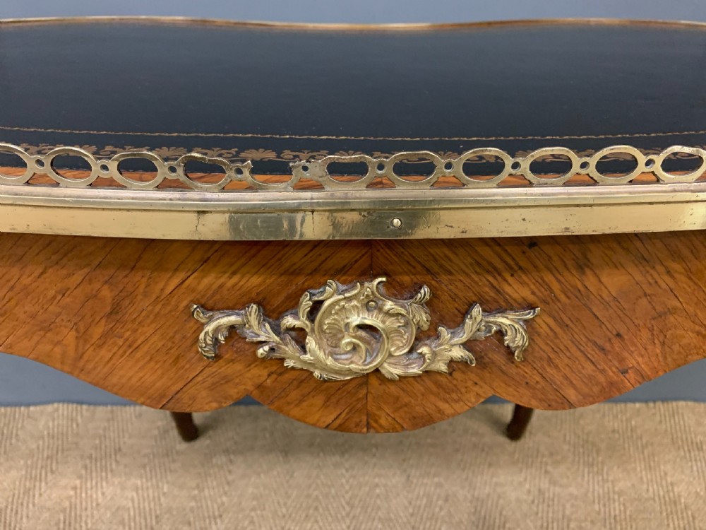 A Victorian kidney-shaped rosewood writing table featuring a dark leather top with gilt tooling, a pierced brass gallery, and cabriole legs with decorative ormolu mounts. View XVIII