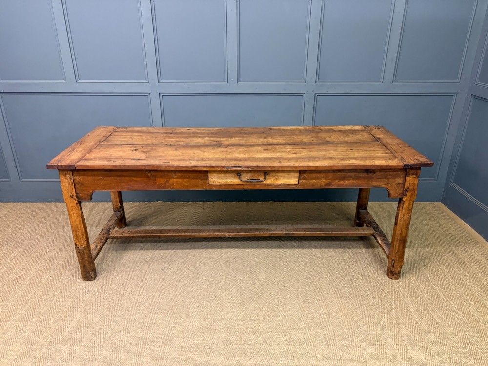 An early 19th-century fruitwood refectory table with a plank top, single side drawer, and stretcher base. View II