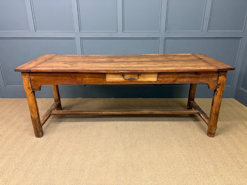 An early 19th-century fruitwood refectory table with a plank top, single side drawer, and stretcher base. View III