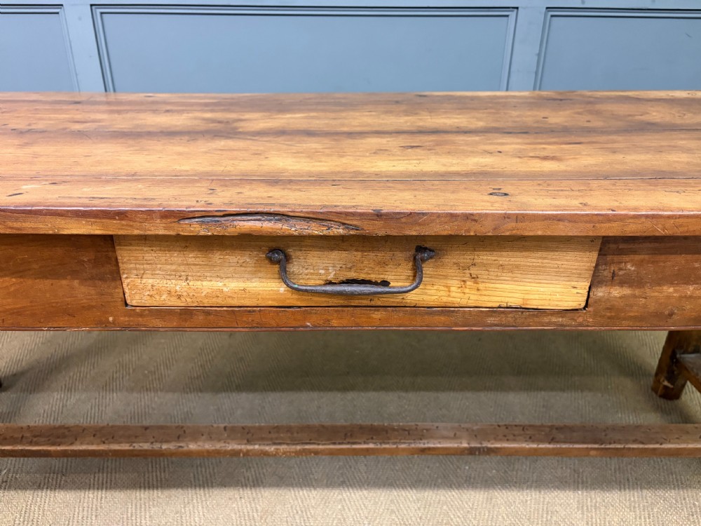 An early 19th-century fruitwood refectory table with a plank top, single side drawer, and stretcher base. View IV
