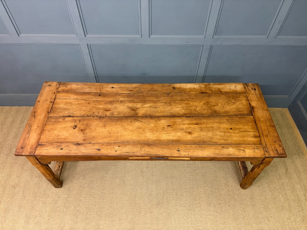 An early 19th-century fruitwood refectory table with a plank top, single side drawer, and stretcher base. View V