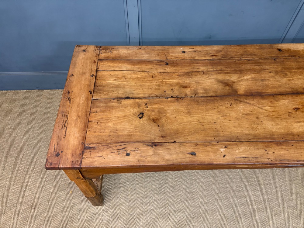 An early 19th-century fruitwood refectory table with a plank top, single side drawer, and stretcher base. View VI
