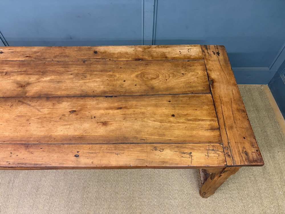 An early 19th-century fruitwood refectory table with a plank top, single side drawer, and stretcher base. View VII