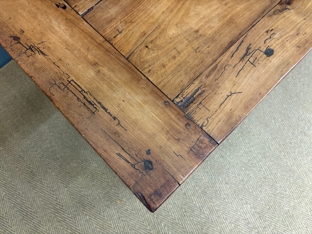 An early 19th-century fruitwood refectory table with a plank top, single side drawer, and stretcher base. View IX