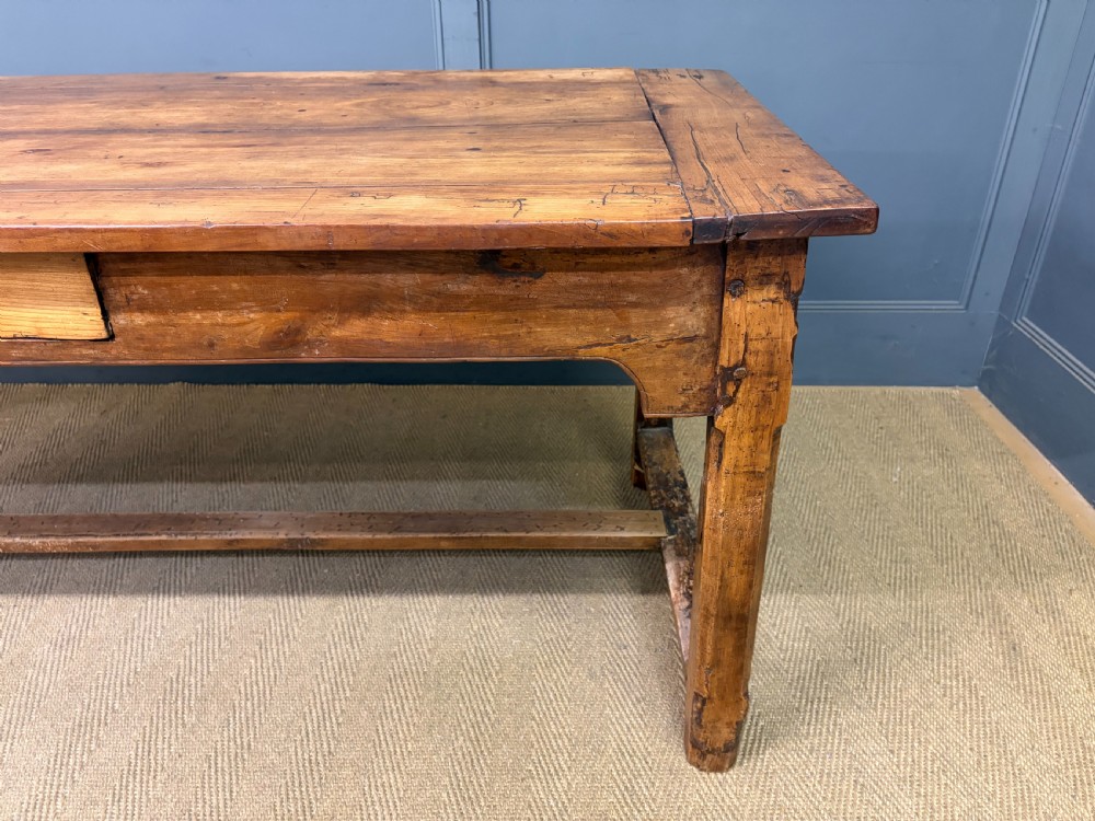 An early 19th-century fruitwood refectory table with a plank top, single side drawer, and stretcher base. View XI