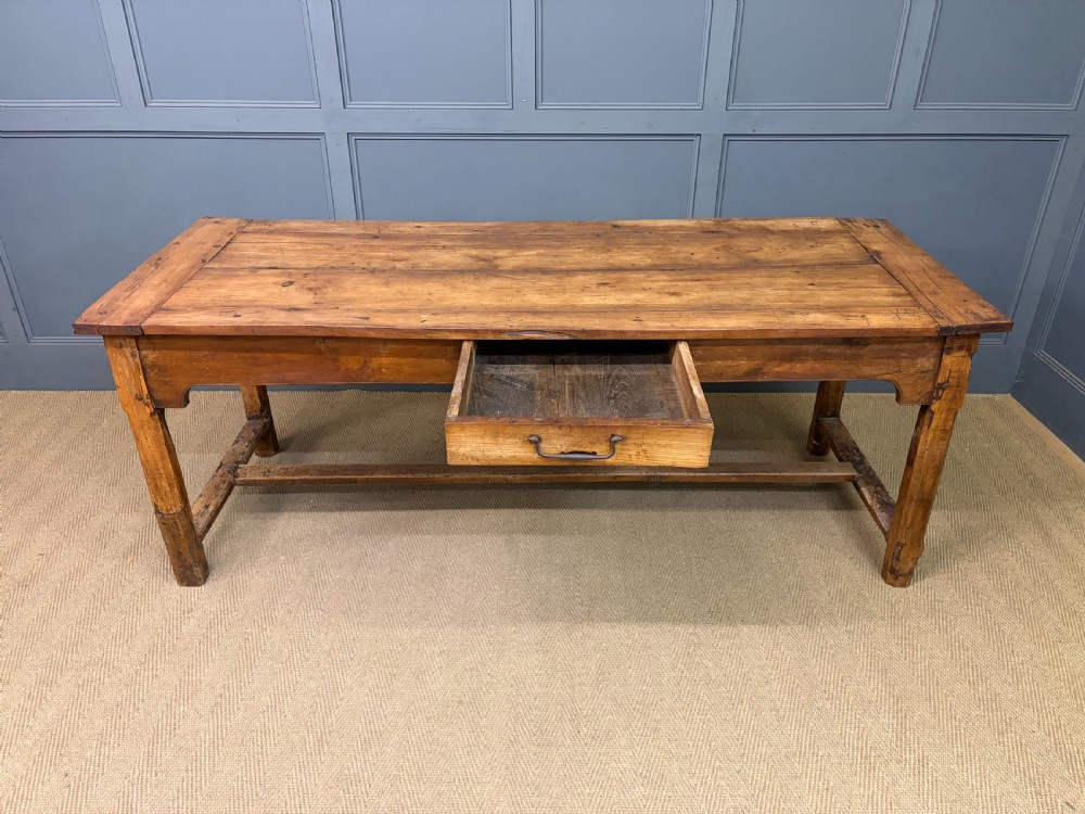 An early 19th-century fruitwood refectory table with a plank top, single side drawer, and stretcher base. View XII