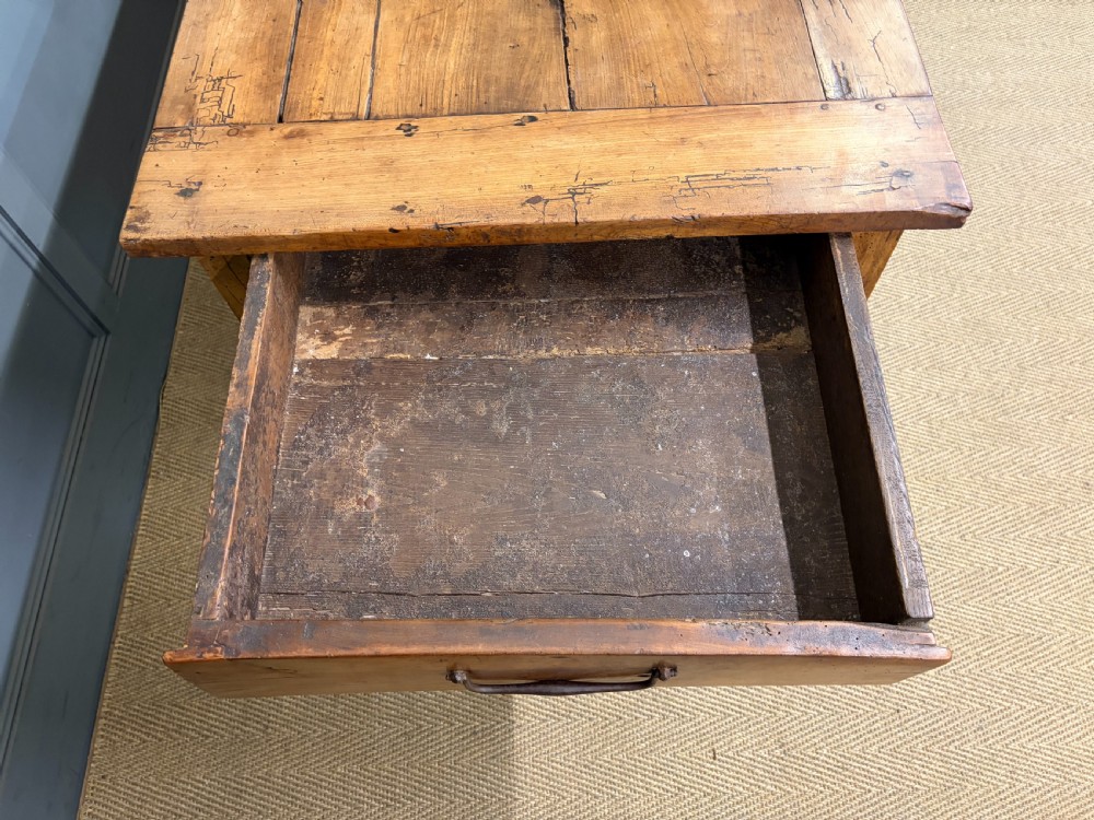An early 19th-century fruitwood refectory table with a plank top, single side drawer, and stretcher base. View XV