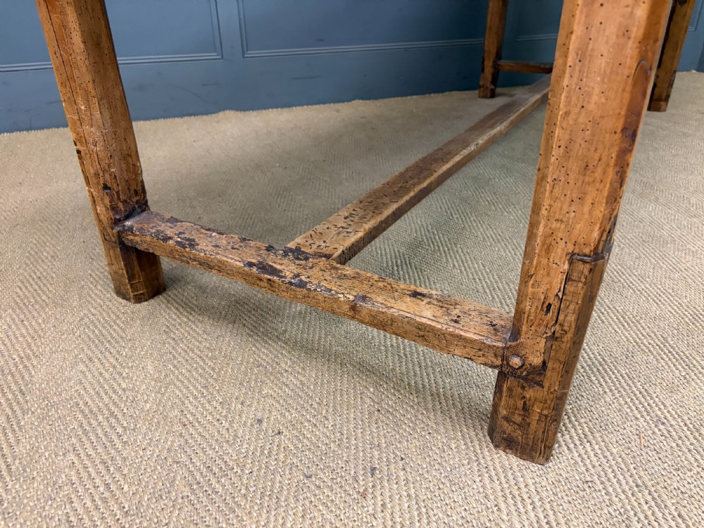 An early 19th-century fruitwood refectory table with a plank top, single side drawer, and stretcher base. View XVIII