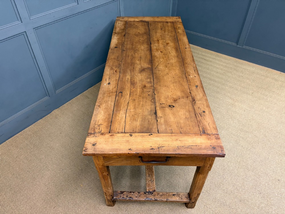 An early 19th-century fruitwood refectory table with a plank top, single side drawer, and stretcher base. View XIX