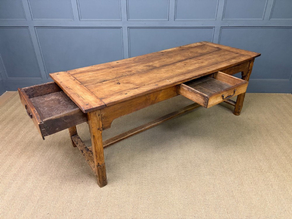 An early 19th-century fruitwood refectory table with a plank top, single side drawer, and stretcher base. View XX