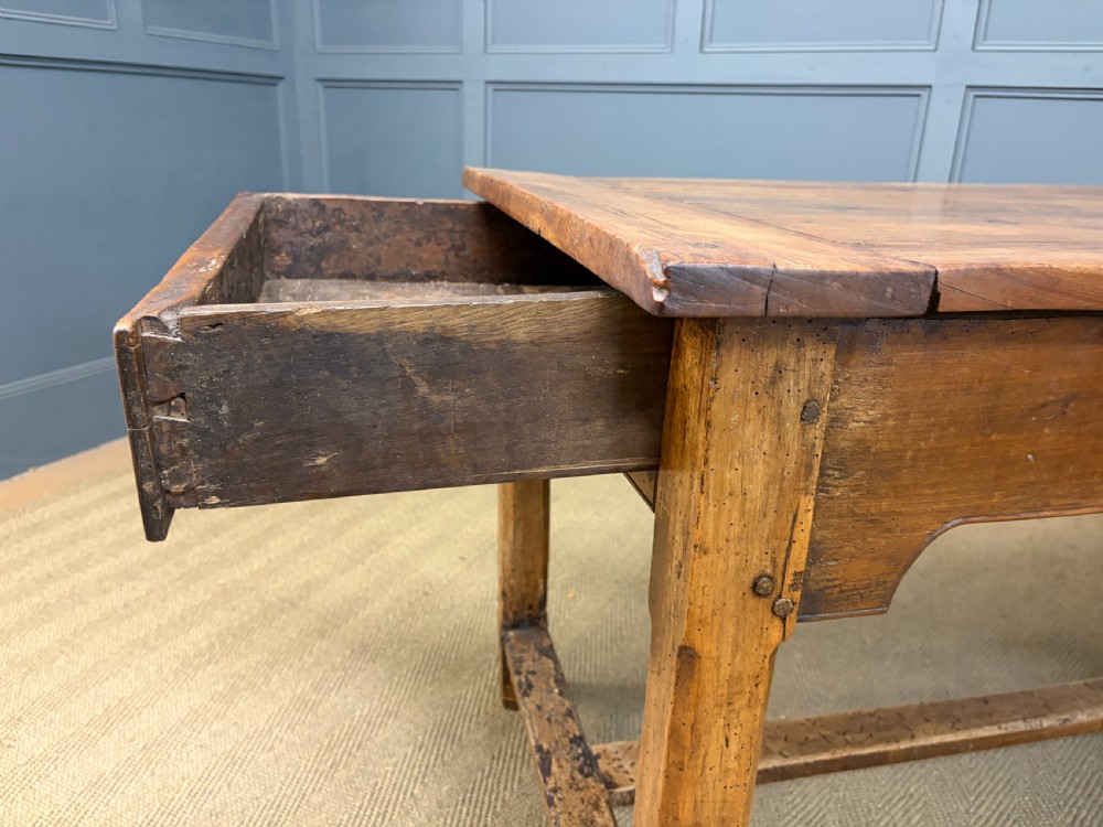 An early 19th-century fruitwood refectory table with a plank top, single side drawer, and stretcher base. View XXI