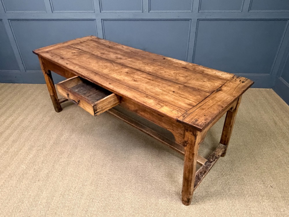 An early 19th-century fruitwood refectory table with a plank top, single side drawer, and stretcher base. View XXIV