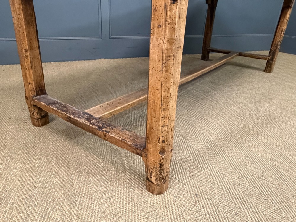 An early 19th-century fruitwood refectory table with a plank top, single side drawer, and stretcher base. View XXVII