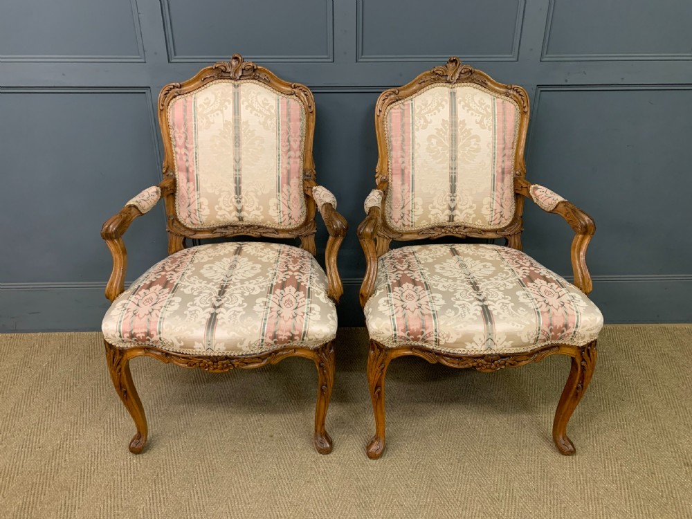 A pair of French carved walnut armchairs featuring cabriole legs and pink and cream patterned fabric upholstery. View II
