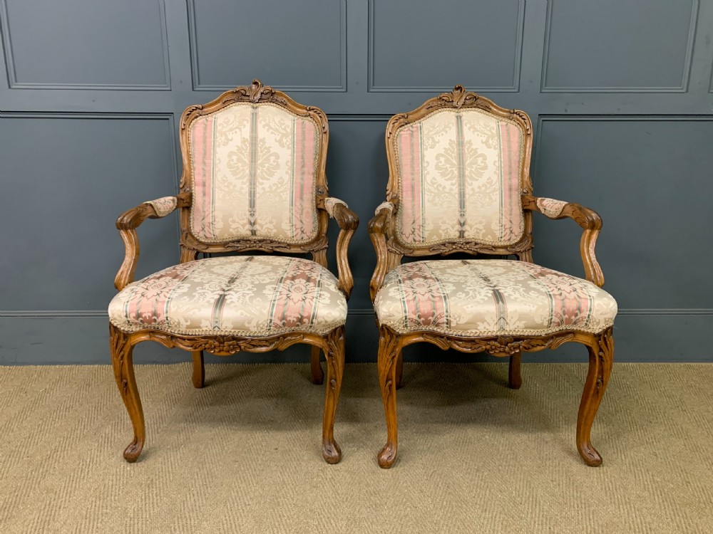 A pair of French carved walnut armchairs featuring cabriole legs and pink and cream patterned fabric upholstery. View III