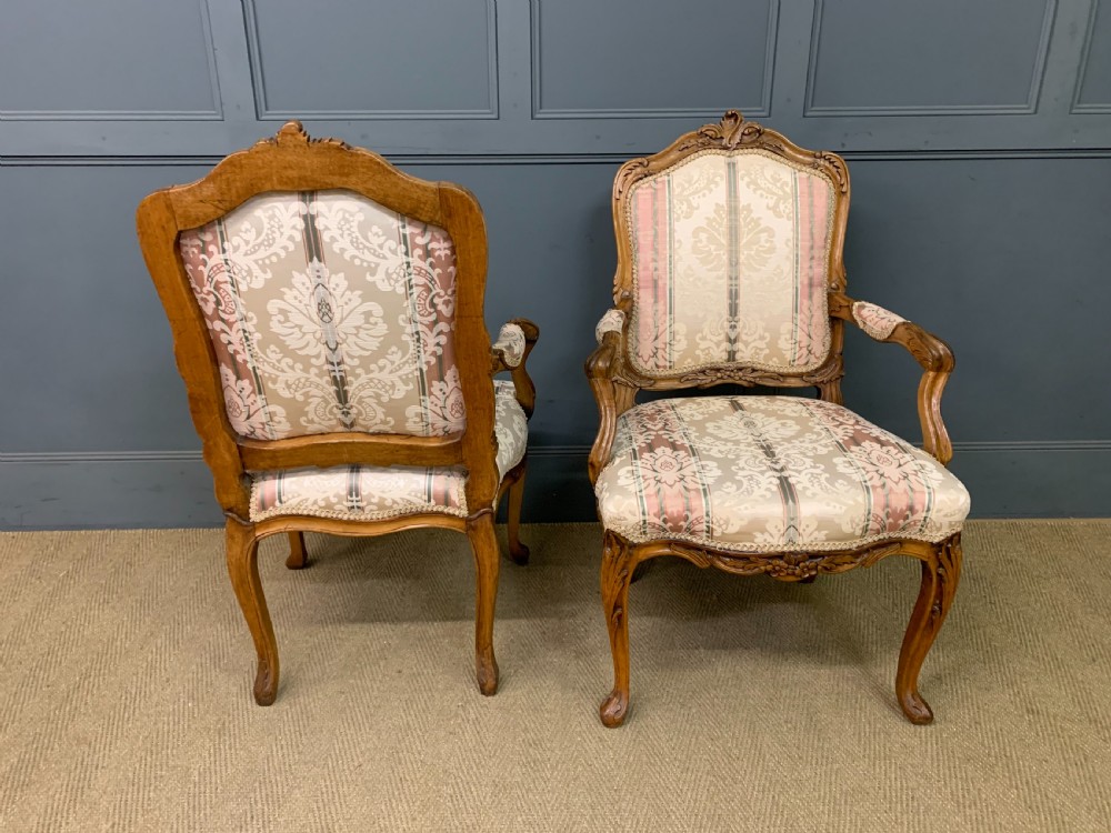A pair of French carved walnut armchairs featuring cabriole legs and pink and cream patterned fabric upholstery. View V