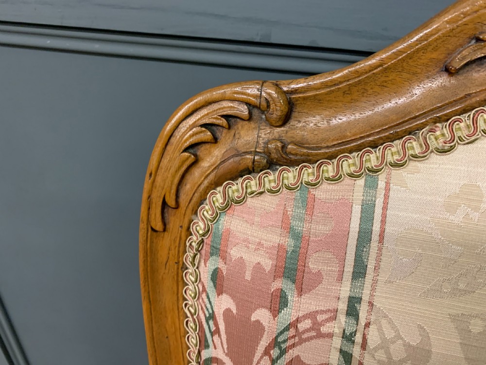 A pair of French carved walnut armchairs featuring cabriole legs and pink and cream patterned fabric upholstery. View IX