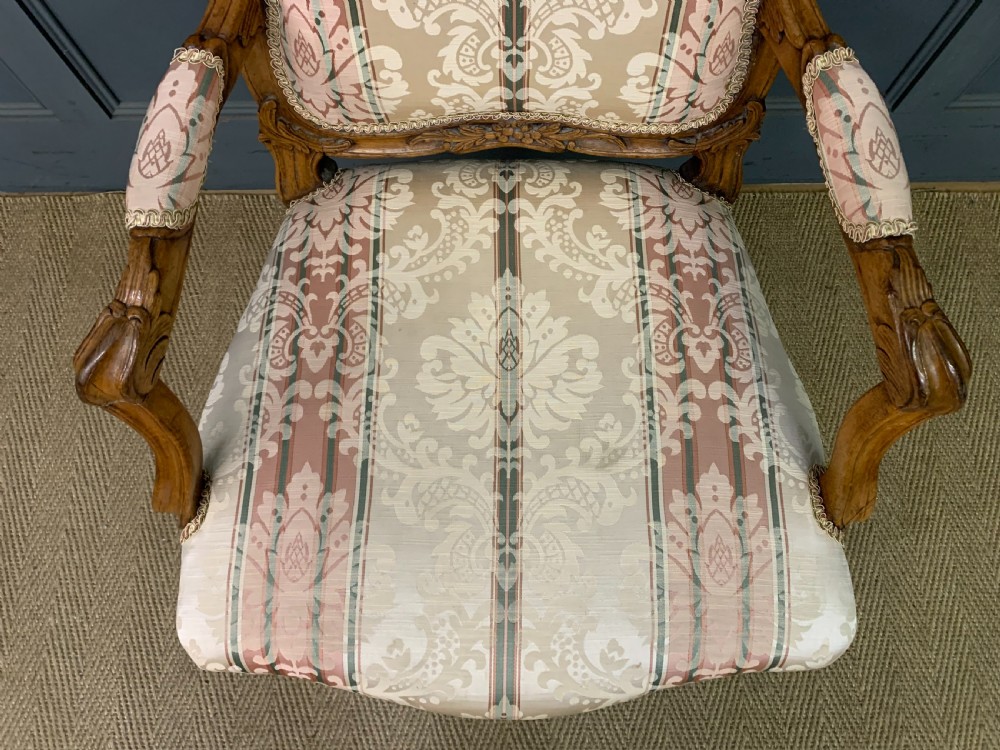 A pair of French carved walnut armchairs featuring cabriole legs and pink and cream patterned fabric upholstery. View XI