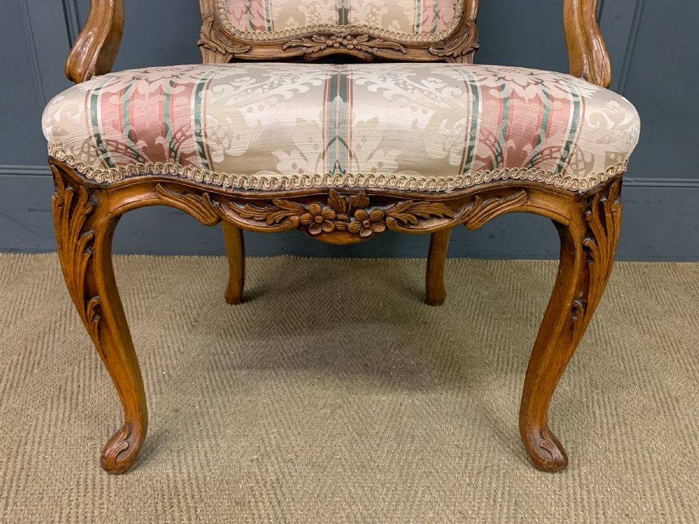 A pair of French carved walnut armchairs featuring cabriole legs and pink and cream patterned fabric upholstery. View XII