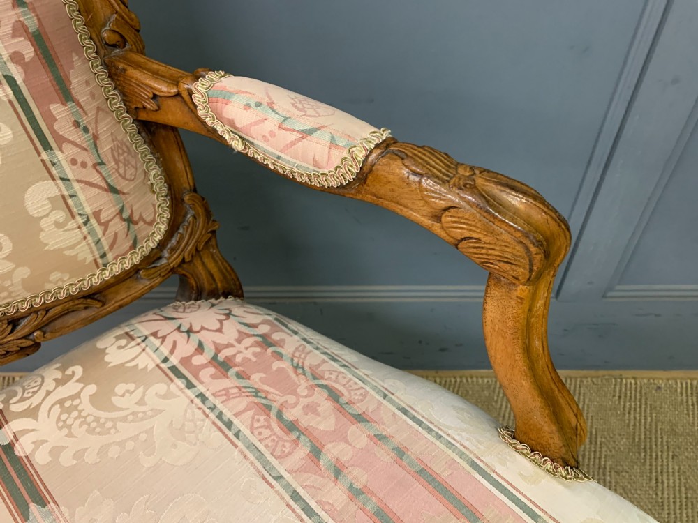 A pair of French carved walnut armchairs featuring cabriole legs and pink and cream patterned fabric upholstery. View XIII